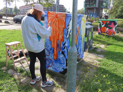 912097 Afbeelding van Melissa de Gier die een van de drie elektriciteitskastjes beschildert, op de hoek van de Van ...